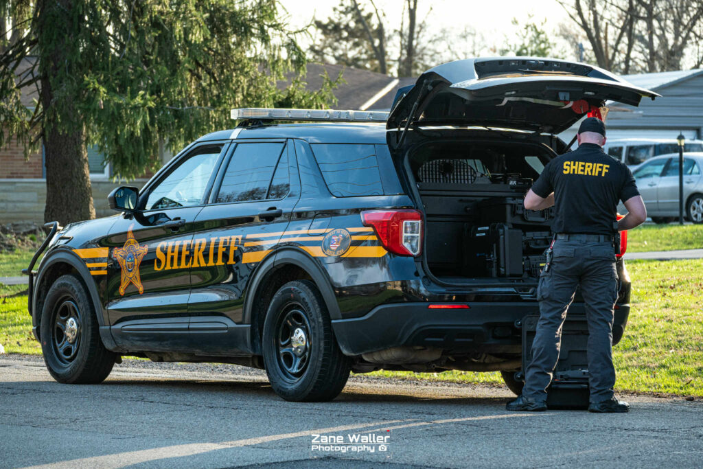 A deputy at the scene of the raid is pictured here getting items from his cruiser. | PHOTO: Zane Weller Photography