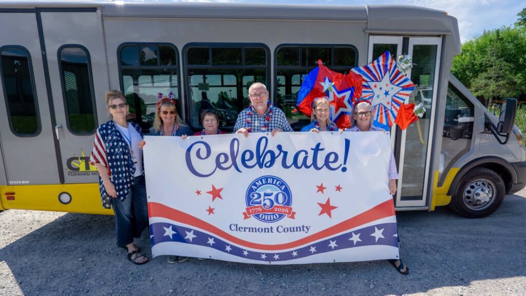 CTC staff pose with an America 250 banner in front of a transit bus