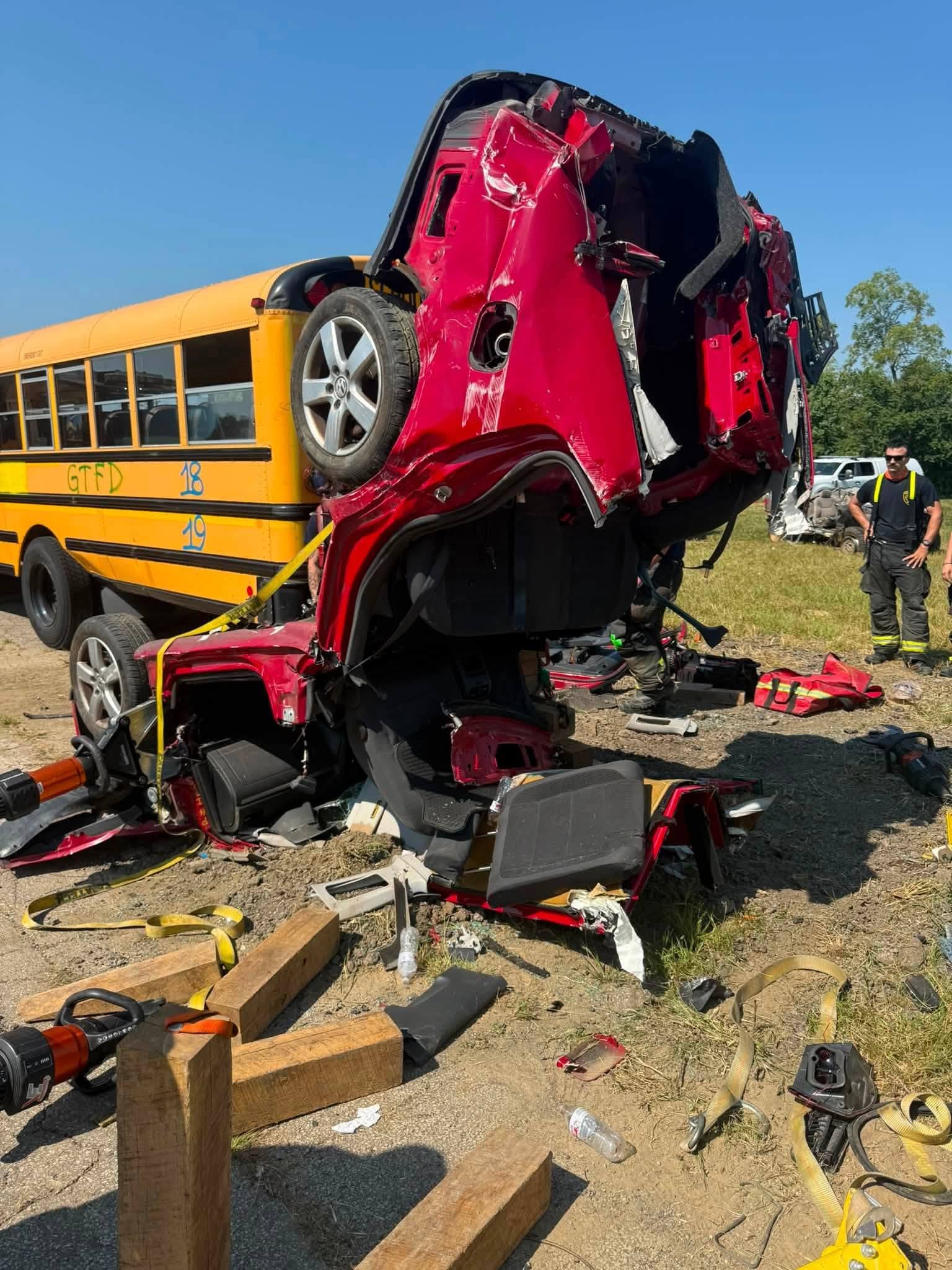 Firefighters work to free a crushed vehicle pinned beneath a school bus during a training exercise