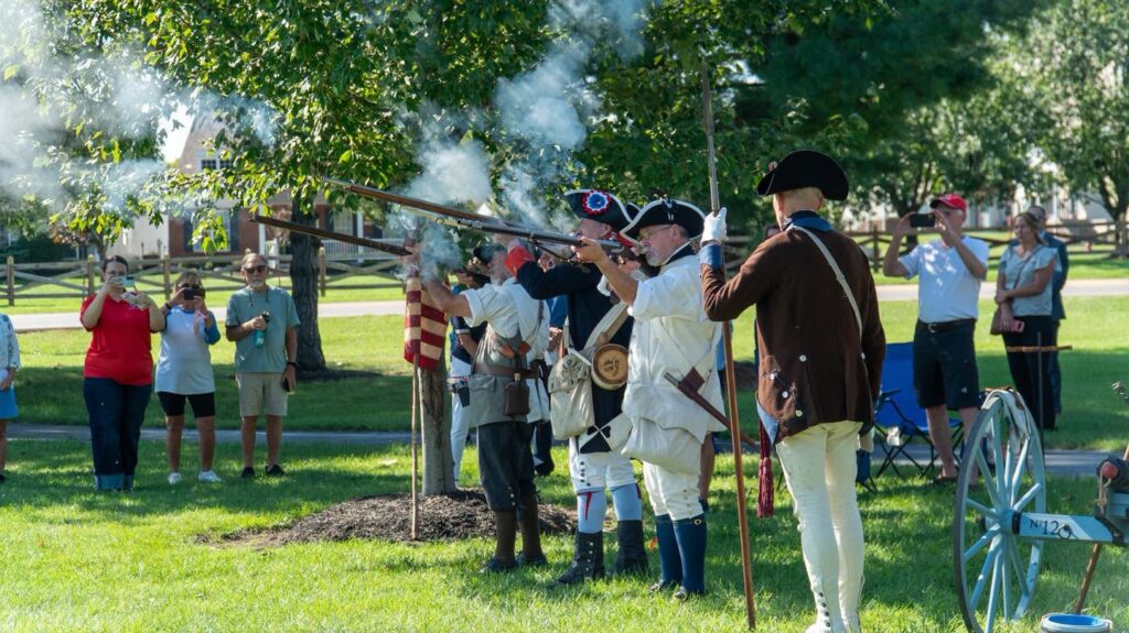 Revolutionary War reenactors fire a musket volley during the ceremony