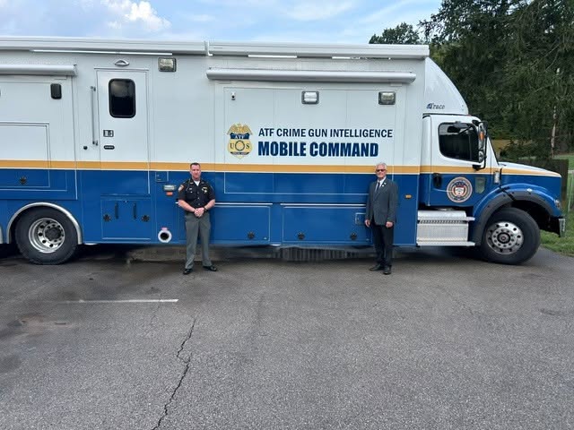 Sheriff Christopher Stratton stands with an ATF official beside the Crime Gun Intelligence Mobile Command vehicle
